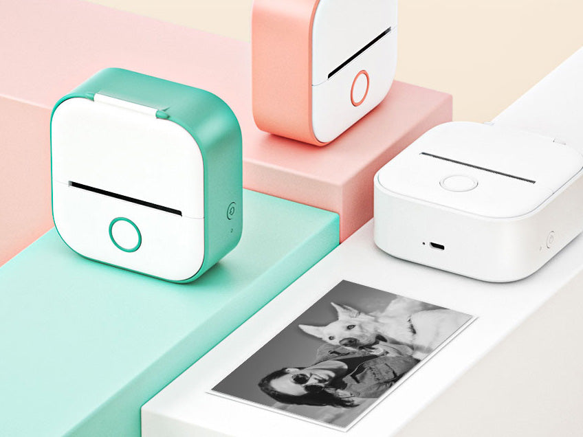 Small portable photo printer on a colorful geometric background with a printed photo of a dog and person.